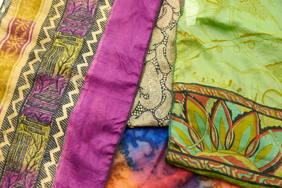 Layered hand-dyed fabrics in purple, green and gold with woven borders